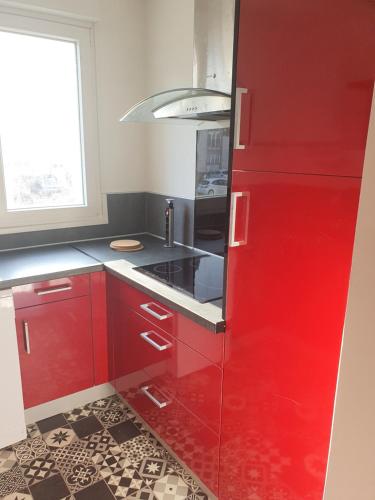 Il comprend une cuisine équipée de placards rouges et d'un réfrigérateur rouge. dans l'établissement Appartement 2 chambres, proximité plage, commerces et centre ville, à Dunkerque