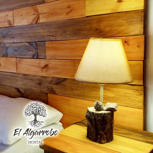 a lamp sitting on a table next to a bed at Hostal El Algarrobo in Casa Grande