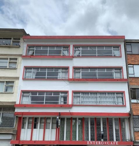 a red and white building with many windows at Hotel Lourdes la 62 in Bogotá