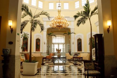 a large lobby with palm trees and a chandelier at Quinta Edén Villahermosa in Villahermosa