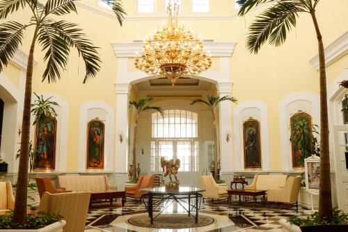 a large lobby with palm trees and a chandelier at Quinta Edén Villahermosa in Villahermosa