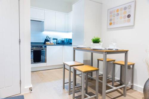 cocina con mesa y taburetes en una habitación en Absolute Stays at The Ziggurat - St Albans-High Street- Near Luton Airport - St Albans Abbey Train station -Close to London- Harry Potter World - The Odyssey Cinema-Contractors -London Road-Business-Leisure, en Saint Albans