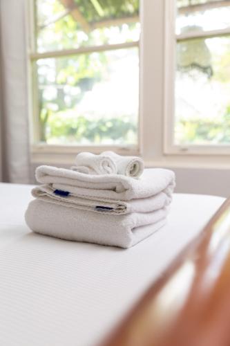 a pile of towels sitting on top of a bed at Lotus Stay Manly - Apartment 31A in Sydney