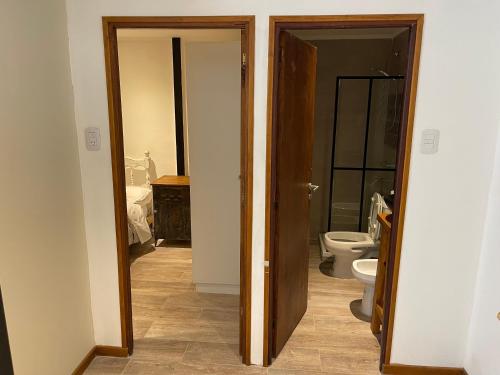 a bathroom with a toilet and a door open at ApartaHotel LaCatedral in Reconquista