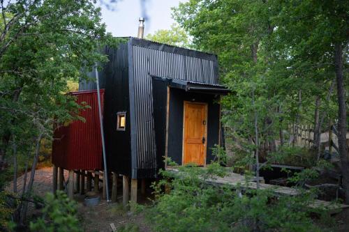 a black house with a wooden door in the woods at Andrómeda Lodge in Las Trancas
