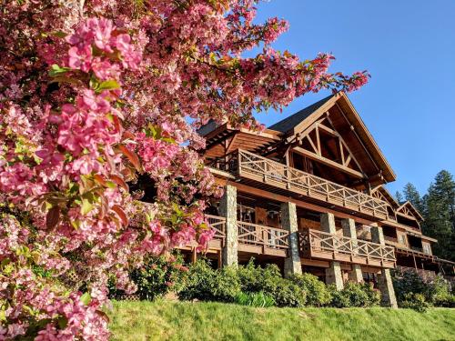 a large wooden house with pink flowers in front of it at Lodge at Sandpoint in Sandpoint