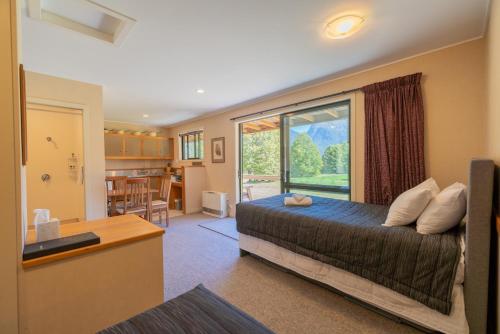 a bedroom with a bed and a large window at Eglinton Valley Camp in Te Anau Downs