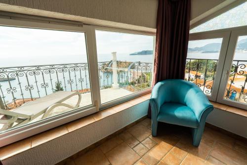 a room with a balcony with a chair and windows at Villa Edelweiss in Sveti Stefan