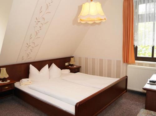 a bedroom with a bed with white sheets at Braugasthof Papiermühle in Jena