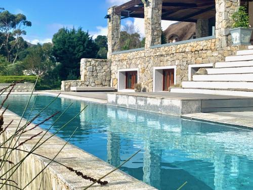 a swimming pool with stairs and a building at The Guardian Hermanus Luxury Self-Catering Hemel en Aarde Valley in Hermanus