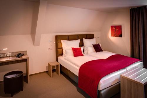 a hotel room with a bed with a red blanket at Weserhotel Schwager in Holzminden