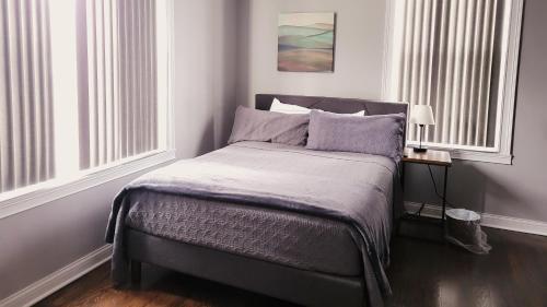 a bed in a room with two windows at Modern style and comfort near UC in Cincinnati
