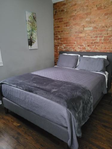 a bed in a bedroom with a brick wall at Modern style and comfort near UC in Cincinnati