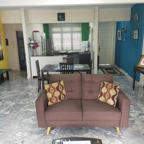 a living room with a brown couch and a table at Relaxing Retreats at Cocobay Apartments in Port Dickson