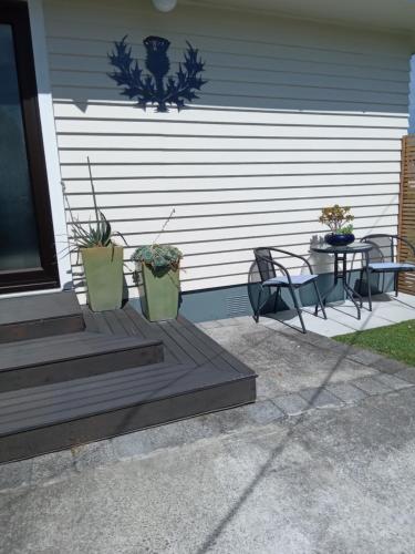 a porch with two chairs and a table with plants at Thistle B&B in Napier