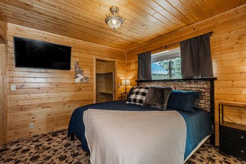 a bedroom with a bed and a flat screen tv at Winterfell Cabin in Rea