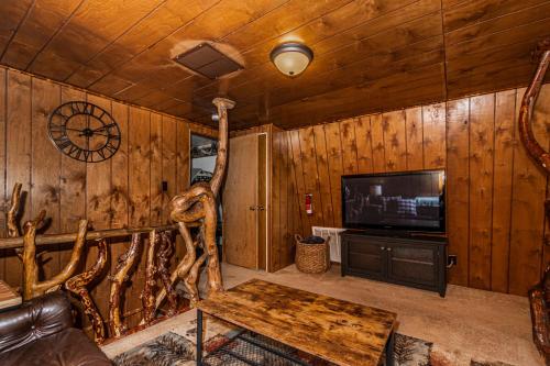 a living room with wooden walls and a tv and a table at Winterfell Cabin in Rea