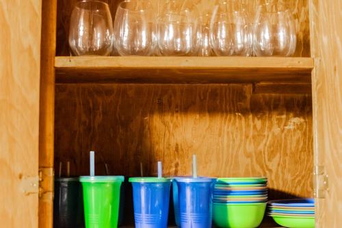 a row of blue and green cups sitting on a shelf at Winterfell Cabin in Rea