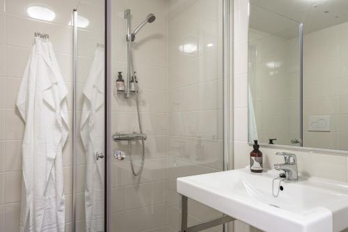 uma casa de banho branca com um chuveiro e um lavatório. em Boo Boo Living em Estocolmo