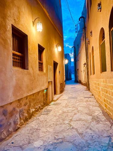 an alley in an old town at night at Jawharat Alaqar Inn نزل جوهرة العقر in Nizwa