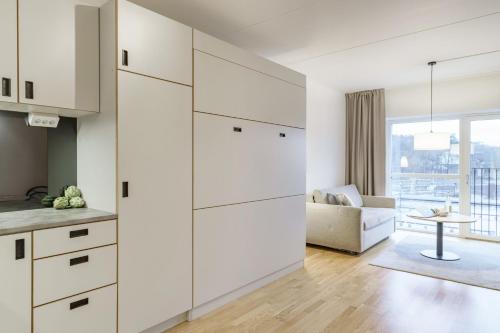 a kitchen with white cabinets and a living room at Boo Boo Living in Stockholm