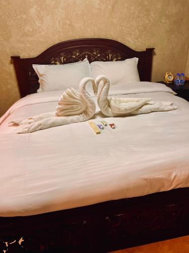 two swans made out of towels on a bed at Jawharat Alaqar Inn نزل جوهرة العقر in Nizwa