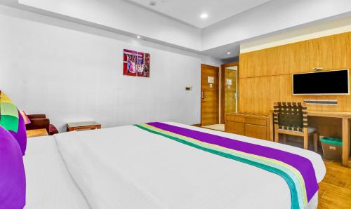 a bedroom with a bed and a desk with a tv at Medora Hotel by Rak Rooms in Kozhikode