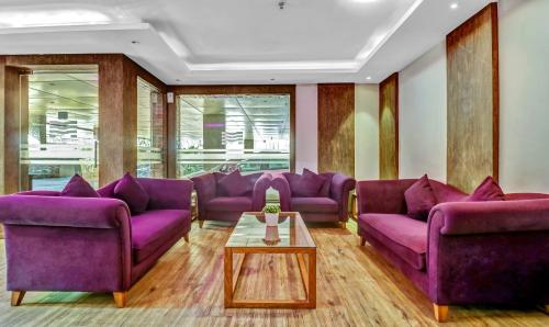 a living room with purple couches and a table at Medora Hotel by Rak Rooms in Kozhikode