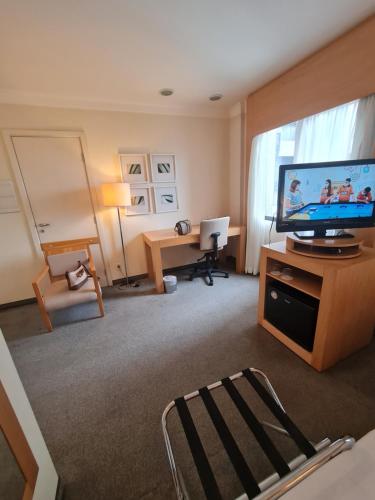 a living room with a flat screen tv and a desk at Nobile Congonhas in Sao Paulo