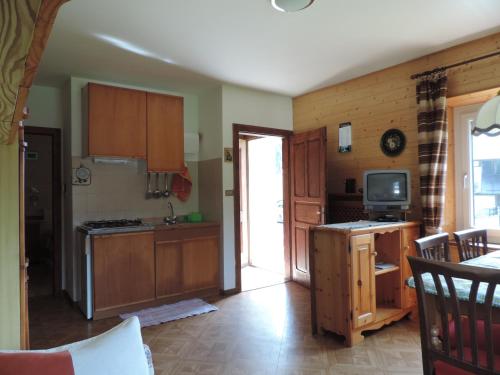 a kitchen with wooden cabinets and a tv in it at Appartamento Piller Roner Paola in Sappada