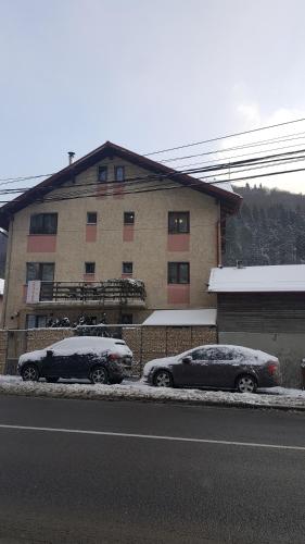 two cars covered in snow in front of a building at CASA RYANA SINAIA in Sinaia