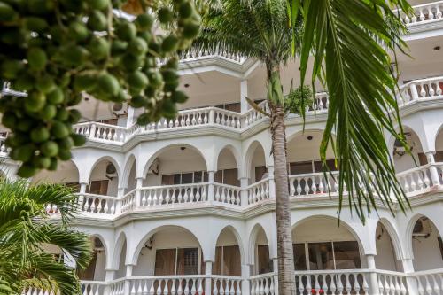 a white building with a palm tree in front of it at CityBlue Creekside Hotel & Suites in Mombasa