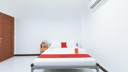 a white room with a bed with a red pillow at RedDoorz @ Guest Hotel Passi City Iloilo in Balatocon