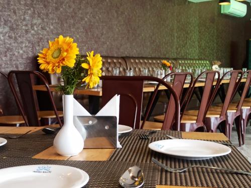 a table with a vase with yellow flowers on it at Indira Nikunj Rubystone Exotic in Rishīkesh