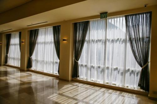 a room with three large windows with curtains at Garden Hotel Boutique & Events in Haifa