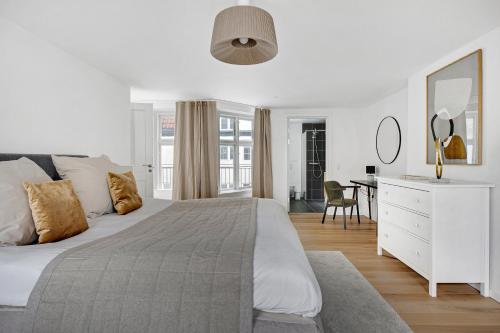 a white bedroom with a large bed and a desk at Sanders Regent - Chic Three-Bedroom Apartment Near Central Square in Copenhagen