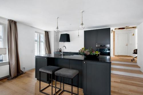 a kitchen with black cabinets and a kitchen island with stools at Sanders Regent - Chic Three-Bedroom Apartment Near Central Square in Copenhagen