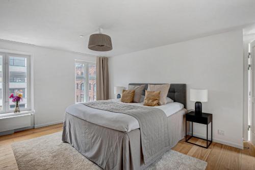 a white bedroom with a large bed and two windows at Sanders Regent - Chic Three-Bedroom Apartment Near Central Square in Copenhagen