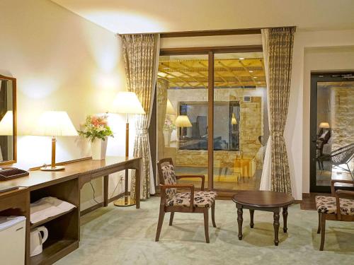 a hotel room with a desk and a table and chairs at 伊豆高原温泉ホテル 森の泉 in Ito