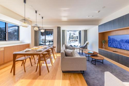 a living room with a dining room table and a tv at ROKA by HHG in Hakuba