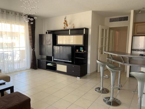 un salon avec une télévision, une table et des chaises dans l'établissement Port Frejus - Le Romanée - Appartement vue mer - 2 Chambres, à Fréjus