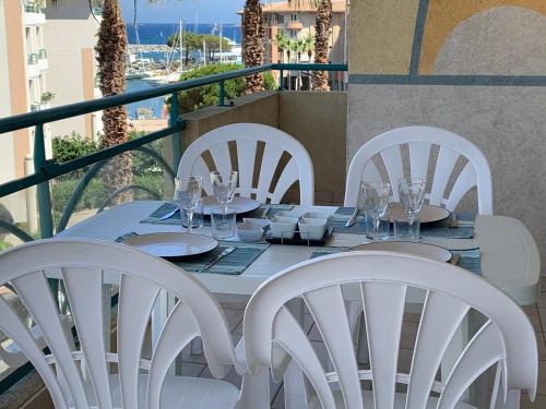 d'une table blanche avec des chaises blanches sur un balcon. dans l'établissement Port Frejus - Le Romanée - Appartement vue mer - 2 Chambres, à Fréjus