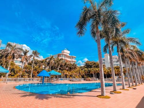 a pool with palm trees and buildings in the background at Nhà Ống Newwave Vũng Tàu - Venuestay in Vung Tau