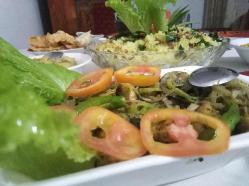 a plate of food with tomatoes and lettuce on a table at Indika's Apartment in Hikkaduwa