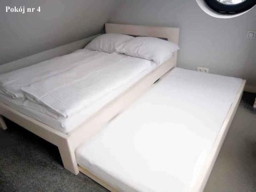 a bed with white sheets and pillows on it at Apartamenty Martushka in Karpacz