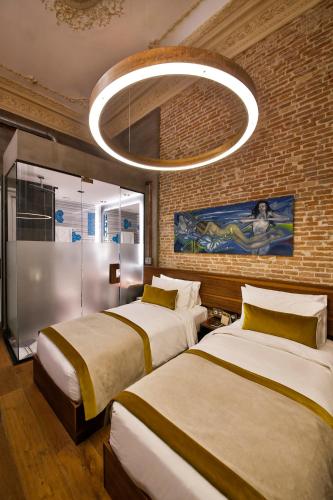 two beds in a hotel room with a chandelier at Hotel The Public - Special Category in Istanbul