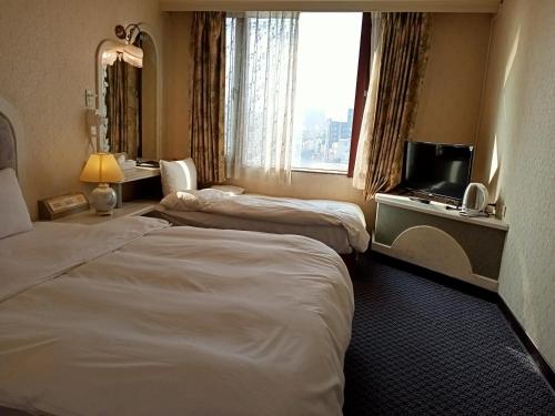 um quarto de hotel com duas camas e uma televisão em Chungli Business Hotel em Zhongli