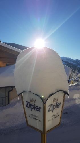 a sign covered in snow in front of a building at Gasthof Schöntal in Oberau