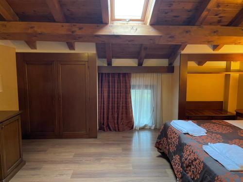 a bedroom with a bed and a wooden ceiling at Hotel Cascina Marisa in Opera