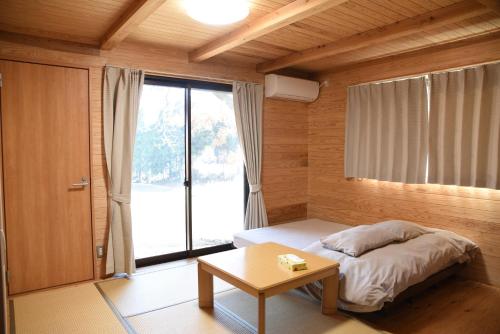 a bedroom with a bed and a table and a window at Wakka in Minami Aso